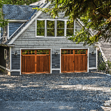 A residential home with two wood garage doors
